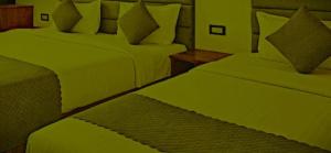 a bedroom with two beds with green sheets and pillows at The Nagpal Hotel in Haridwār