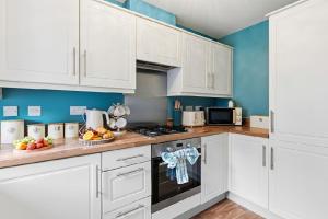 a kitchen with white cabinets and wooden counter tops at Home Comforts Await! 3bed 2.5bath in Ellesmere Port