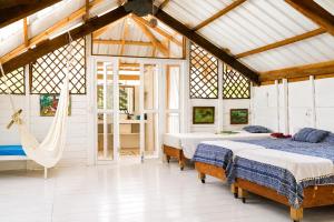 a bedroom with two beds and a hammock in it at Hotel Fuerte Mayal in Puerto Limón