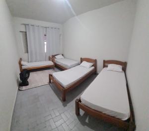 a room with three beds and a couch and a window at Beach Hostel do Japa in Ubatuba