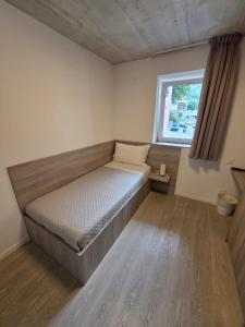 a small bedroom with a bed and a window at Regina by GoAcademy in Agno