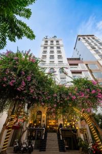 a tall white building with pink flowers on it at Le House Boutique Hotel - 100m to the beach in Danang