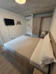 a bedroom with a large bed and a flat screen tv at Regina by GoAcademy in Agno +15 photos