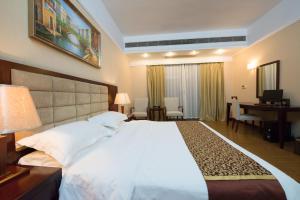 1 dormitorio con 1 cama blanca grande y escritorio en 悦丰酒店广州银丰国际公寓北站店, en Huadu
