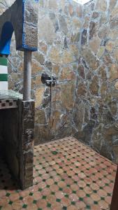 a stone wall with a shower in a room at Dar chez bassou in Imilchil