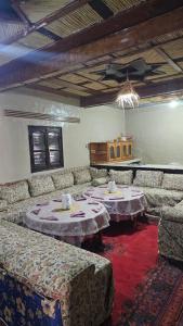 a living room with couches and tables in a room at Dar chez bassou in Imilchil