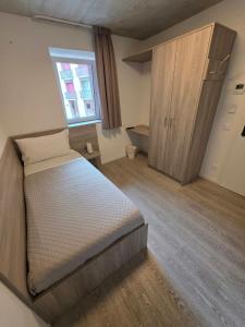 a small bedroom with a bed and a window at Regina by GoAcademy in Agno