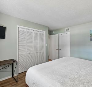 a bedroom with a white bed and a closet at Edgewater Villa #2604 in Panama City Beach