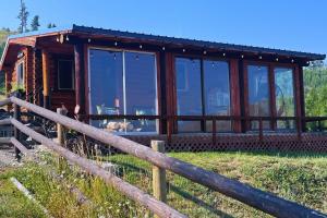 a log cabin with a fence in a field at Cozy Cabin Oxen-Le-Fields Montana in Conner