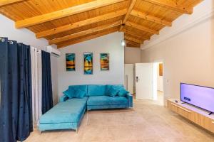 a living room with a blue couch and a flat screen tv at Villa The Old Bakery in Qeparo