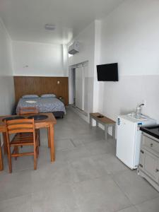 a room with a table and a bed and a kitchen at Pousada Rota do Sol Bombinhas Suítes e Flats - café da manhã servido de nov a páscoa in Bombinhas