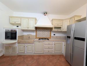 a kitchen with white cabinets and a refrigerator at La Piccola Atene Oasi in Strettoia