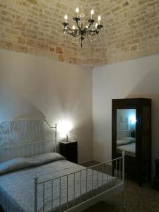 una camera con letto, lampadario a braccio e specchio di Antica Casa "Lelays" a Ostuni