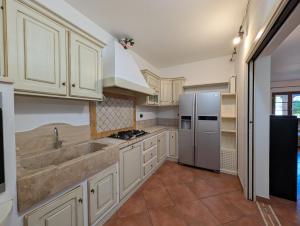 a kitchen with white cabinets and a stainless steel refrigerator at La Piccola Atene Oasi in Strettoia
