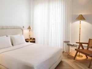 a bedroom with a large white bed and a chair at ATHENA Pallas in Athens +13 photos