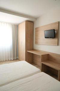a room with two beds and a tv on a wall at Hostal Guadiana in Ruidera