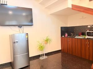 a kitchen with a refrigerator and a tv on the wall at Yelagiris Honey Stay in Yelagiri