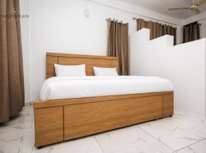 a bedroom with a wooden bed with white sheets at Courts Plaza Apartments in Bawaleshi