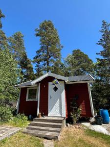 a red house with a white door and stairs at Cozy cottage on Värmdö in Djurhamn