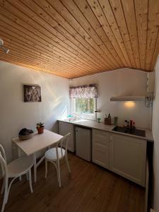 a kitchen with a wooden ceiling and a table at Cozy cottage on Värmdö in Djurhamn