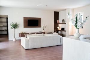 a living room with a white couch and a tv at Stadtmauerloft - Premium Apartment in Eisenstadt
