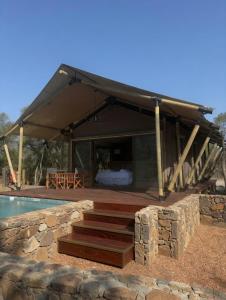 a pavilion with a bed and a swimming pool at Ndzhaka Tented Camp in Manyeleti Game Reserve