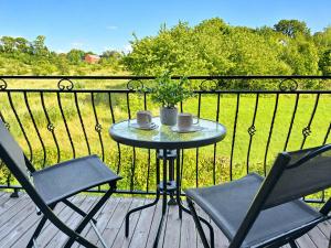 a table on a deck with two chairs and a plant at Morenowa Dolina Rusinowo in Rusinowo