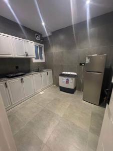 a kitchen with white cabinets and a refrigerator at المارنز in Baghdād