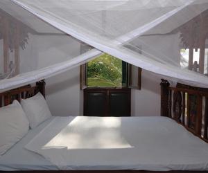 a bedroom with a large white bed with a window at The Old Boma Hotel in Mtwara