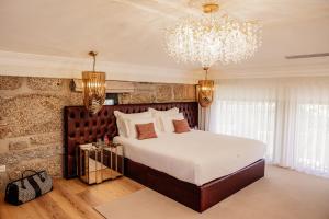 a bedroom with a large bed and a chandelier at Quinta Linhas da Primavera in Guimarães