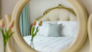 a mirror reflecting a bed with a pillow and flowers at Gapyeong Elin Pension in Gapyeong