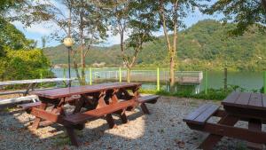 a picnic table and benches in front of a lake at Gapyeong Elin Pension in Gapyeong