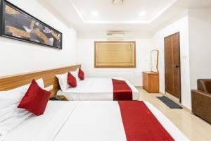 a hotel room with two beds with red pillows at Hotel Faaz international in Thottada