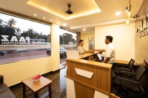 two men standing at a reception desk in a lobby at Hotel Faaz international in Thottada