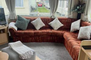 a living room with a brown couch with pillows at 2 Bedroom Caravan - Sleeps 6 - Parking Seaside in Abergele
