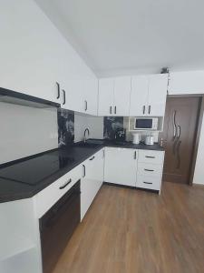 a kitchen with white cabinets and a black counter top at The Cozy Backyard Home- satu Mare in Satu Mare