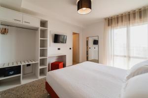 a white bedroom with a bed and a tv at Hotel Delaville Frontemare in Lido di Jesolo +84 photos
