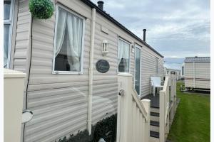 a white house with a porch and a fence at 2 Bedroom Caravan - Sleeps 6 - Parking Seaside in Abergele