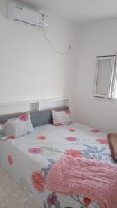 a bedroom with a bed with a flowered blanket on it at Najib in Djerba