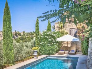 a swimming pool in a yard with an umbrella and chairs at Villa Sunset in Gordes in Gordes