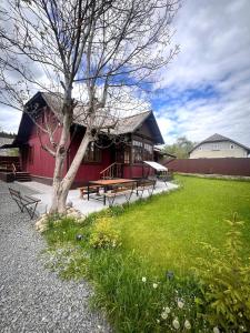 a red building with picnic tables and a tree at Mover mount apart in Skole