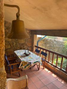a table and chairs on a balcony with a bell at Casa da Costeira in Figueiró