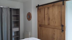 a bedroom with a wooden door and a clock at Gîte La Ferme Ecole in Perrou