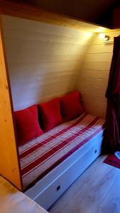 a bed in a room with red pillows on it at La Cabane Forestière in Voussac