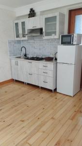 a kitchen with a white refrigerator and a wooden floor at Anas apartments in Zugdidi
