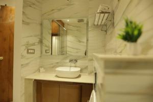 a white bathroom with a sink and a mirror at The Woods by CASA D' GAVA in Lucknow