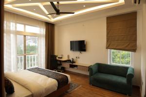 a bedroom with a bed and a chair and a tv at The Woods by CASA D' GAVA in Lucknow