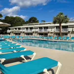 a row of blue and white lounge chairs in a swimming pool at Players Club Resort in Hilton Head Island