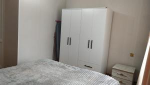 a bedroom with a bed and a white cabinet at Anas apartments in Zugdidi