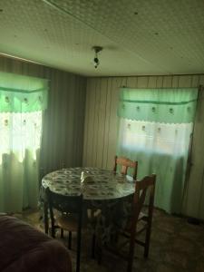 a dining room with a table and chairs and curtains at Mobil-home in Rebaïb +2 photos